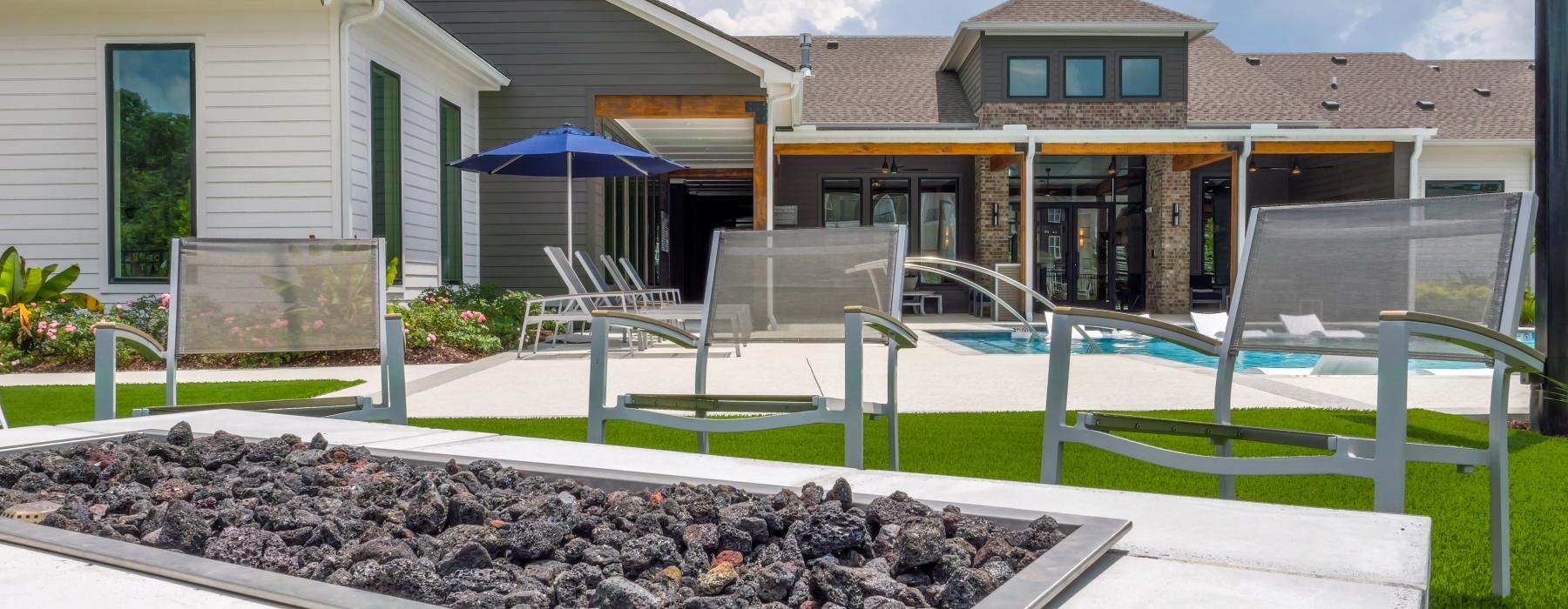 a swimming pool in front of a building with chairs and a fire pit